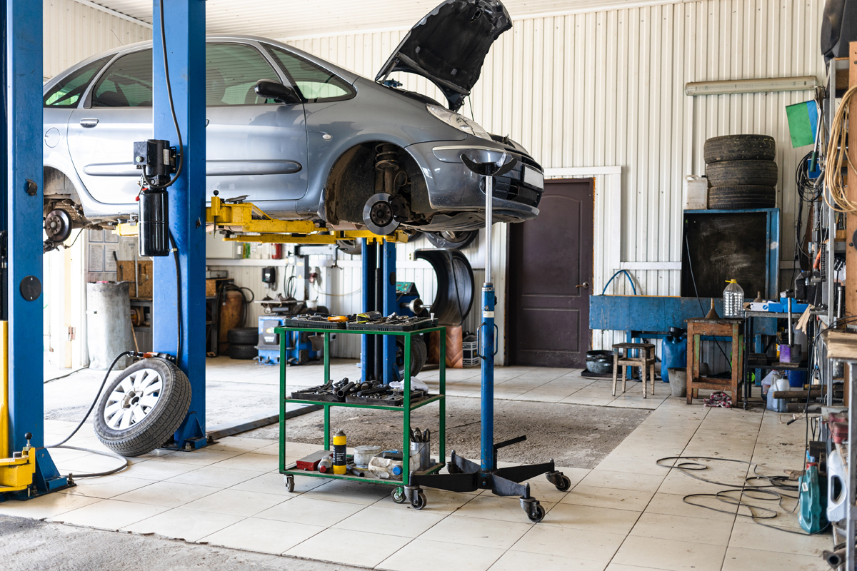 small car on a blue car lift in an automotive shop