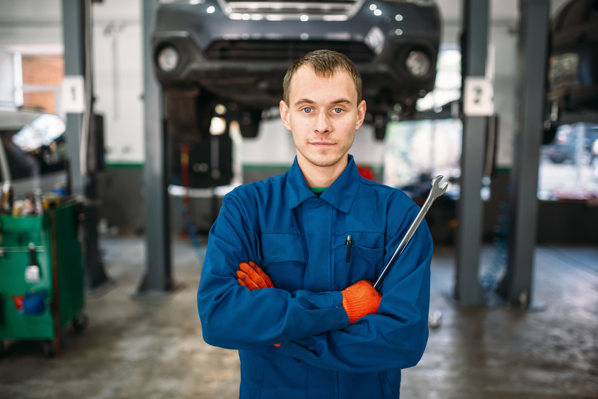 mechanic standing in front of a car lift with a wrench