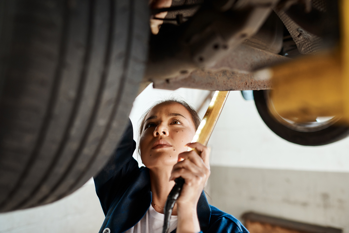 female working on a lifted car